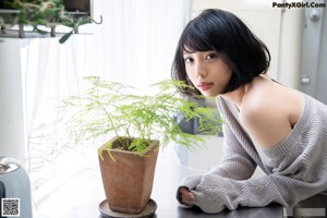 A naked asian woman sitting on a kitchen counter.