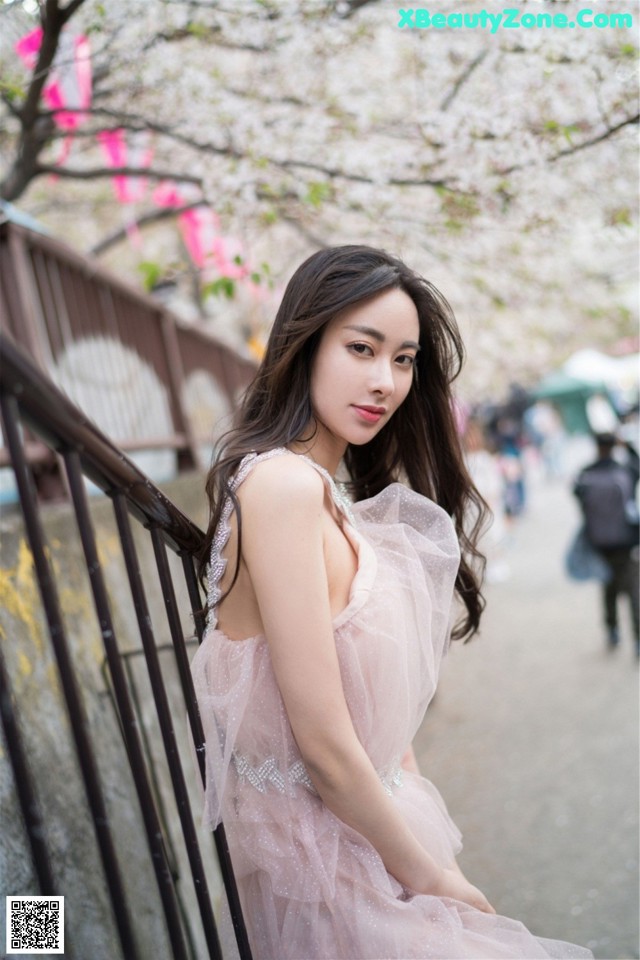 A woman in a pink dress posing for a picture.