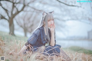 A woman in a blue dress sitting in a field.