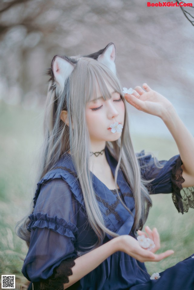 A woman in a blue dress with a cat ears on her head.