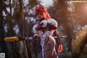 A woman with red hair holding a sword in the woods.