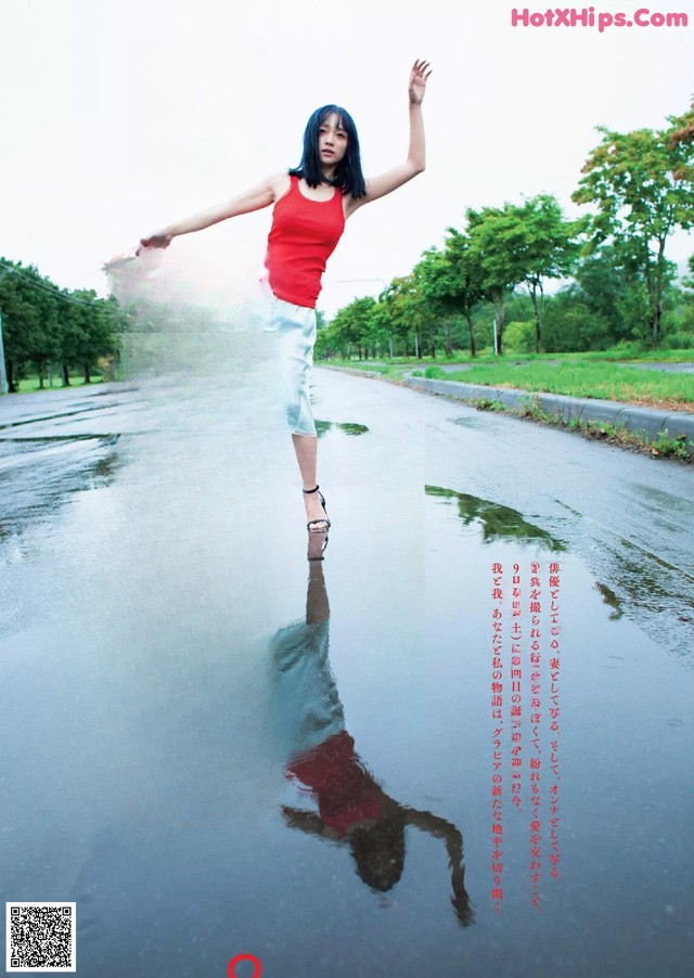 A woman in a red top and white skirt standing in the middle of a road.