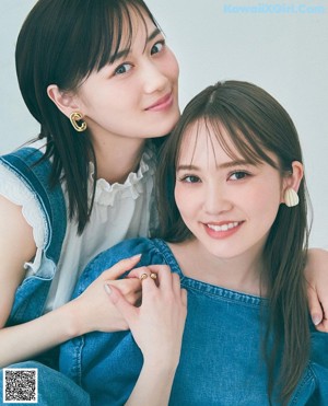 A couple of women sitting next to each other on a bed.