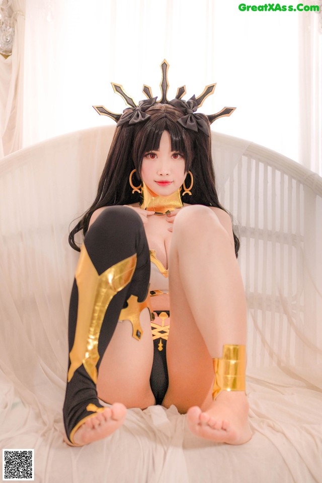 A woman in a black and gold outfit sitting on a bed.
