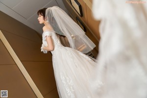 A woman in a wedding dress and high heels standing in a closet.