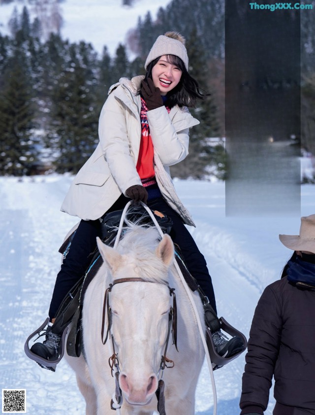 A woman riding on the back of a white horse.