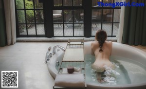 A person sitting on a wooden deck looking out a window.