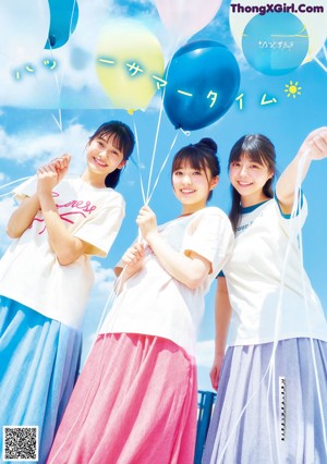 A group of young women sitting on the ground holding balloons.