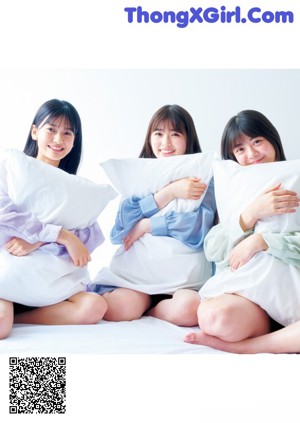 A group of young women sitting on top of a bed.