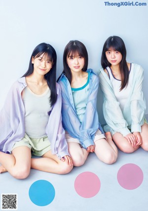 A group of young women sitting on the ground holding balloons.