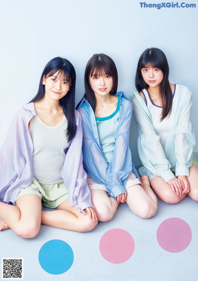 A group of three young women sitting on the ground.