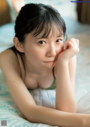 A woman with long black hair in a white tank top.