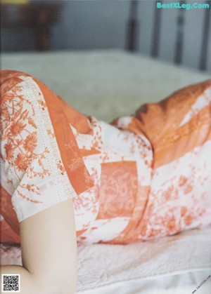 A woman laying on top of a bed next to a pillow.