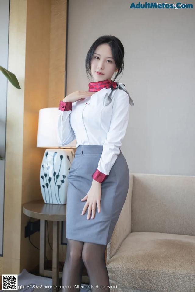 A woman in a white shirt and gray skirt posing for a picture.