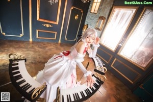 A woman in a white dress playing a piano.