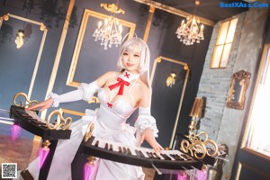 A woman in a white and pink dress sitting on a white piano.