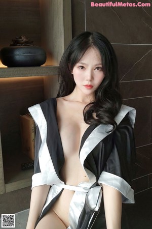 A woman in a black and white robe sitting in a bathtub.
